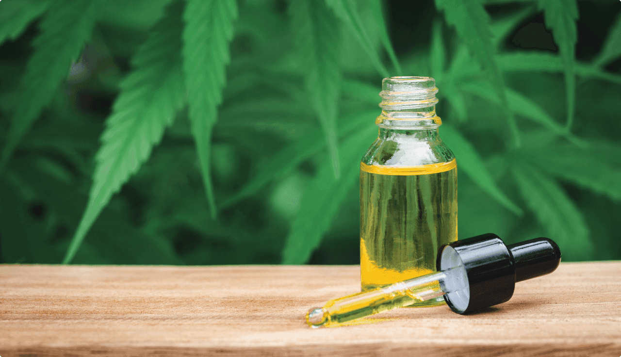 Pipetten-Flasche mit Cannabisblättern im Hintergrund